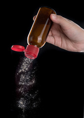 Hand holding a bottle of pepper on black background,pepper shaker