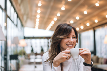 Portrait of attractive woman drinking coffee in modern cafe.