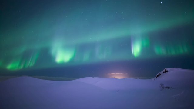 Colorful aurora borealis sprites dancing over deep snow winter lanscape Iceland.