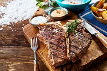 Foto op Plexiglas Piece of barbecued t-bone steak on wooden board © exclusive-design