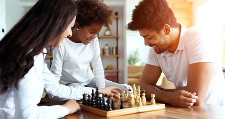 Happy family playing chess together at home