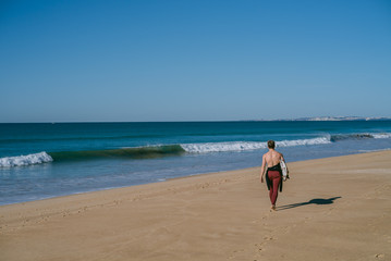Fototapeta na wymiar Man on the beach with surfboard in Portugal warming up