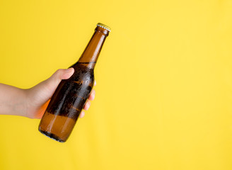 Main tenant une bouteille de bière avec un espace de texte sur fond jaune