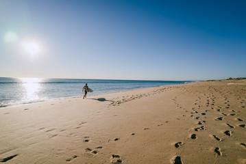 Man running with surfboard on a beach in Portugal