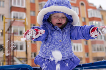 little girl playing snowballs on a winter day