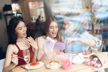 Three girls are sitting together in a cafe.