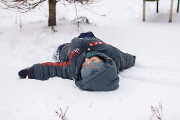 Fototapeta na wymiar little boy lies on the snow