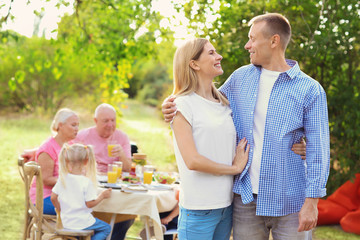Happy couple with family having barbecue party outdoors