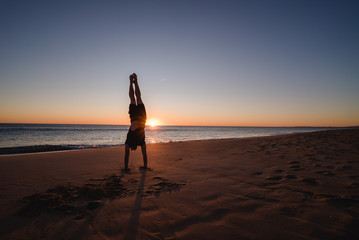 Man doing handstands on the beach at sunset in Portugal