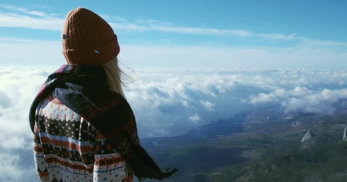 Woman enjoying landscape in mountains over clouds Travel Lifestyle concept adventure vacations outdoor happy emotions girl wearing winter clothing knit hat scarf and sweater