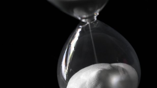 Passing time of hourglass close-up isolated on black