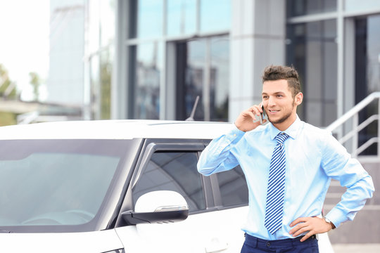 Salesman Talking On Phone Near New Car Outdoors