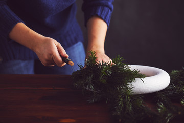 Female florist fixing branches on christmas wreath