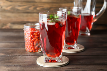 Glasses with healthy goji juice on wooden table