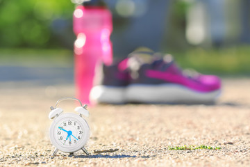 Alarm clock and sport stuff on background. Morning routine concept