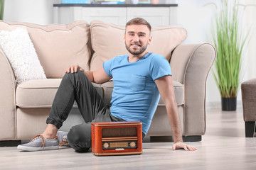 Young man listening to radio while sitting on floor in room