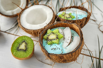 Coconut shell with yummy spirulina smoothie on wooden table. Healthy vegan food concept