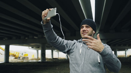 Boxer man having video chat on smartphone with friends after workout at urban location outdoors in...