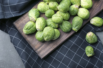 Wooden board with fresh raw Brussels sprouts on table