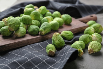 Wooden board with fresh raw Brussels sprouts on table