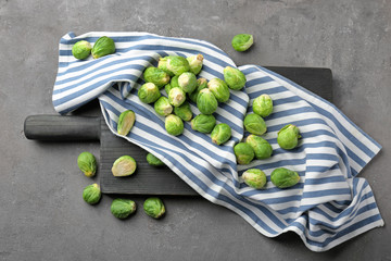 Wooden board with fresh raw Brussels sprouts on table
