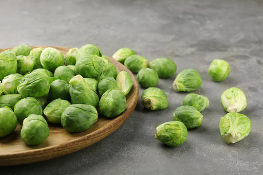 Wooden plate with fresh raw Brussels sprouts on table