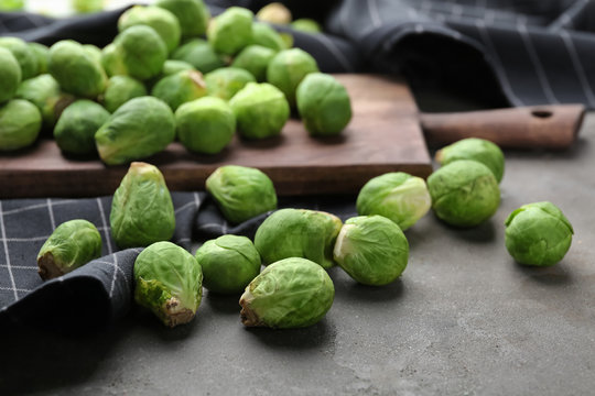 Wooden board with fresh raw Brussels sprouts on table