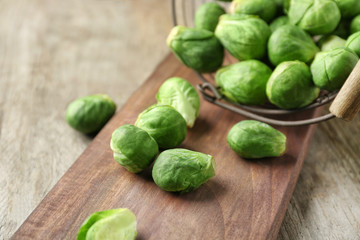 Basket with fresh scattered Brussels sprouts on wooden background