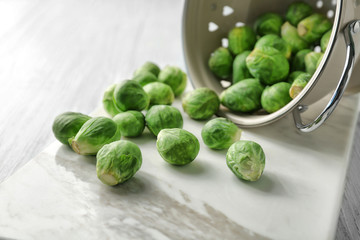 Colander with scattered Brussels sprouts on table