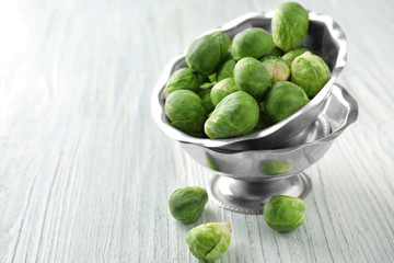 Bowl with raw Brussels sprouts on wooden background