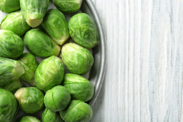 Plate with raw Brussels sprouts on wooden table, closeup