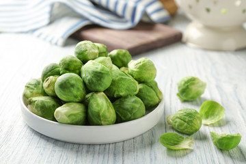 Plate with fresh raw Brussels sprouts on wooden table