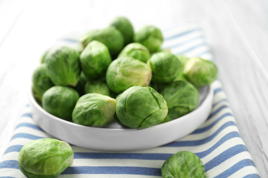 Plate with fresh raw Brussels sprouts on striped cloth