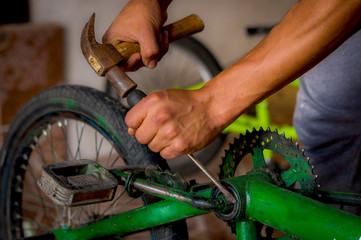 Close up of a man working with a hammer over the bicycle pedal in a workshop in the repair process