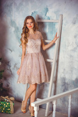 Pretty happy young woman in beautiful lace pastel dress celebrate christmas at home. Christmas concept, female fashion. Lady in romantic dress posing in cozy apartments decorated for New year