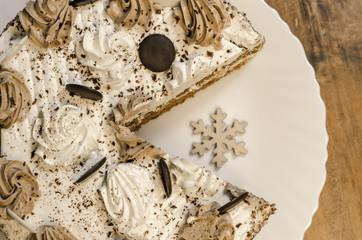 .Closeup delicious homemade sliced tasty chocolate cake on christmas wooden table background. Cakes and new year snowflake. Honey cake with biscuits.