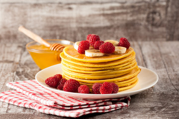 Fresh made delicious pancakes with berries, blackberries, raspberries, banana, honey and maple syrup. Healthy morning breakfast concept.