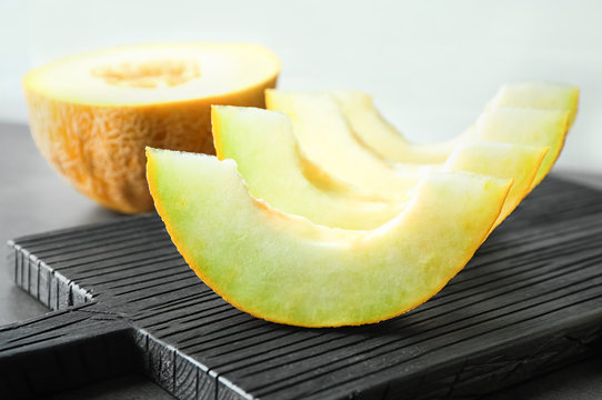 Wooden board with yummy melon slices on table