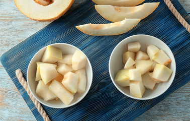 Bowls with yummy melon slices on wooden table