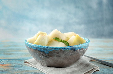 Bowl with yummy melon slices on wooden table
