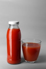 Bottle and glass with juice on light background