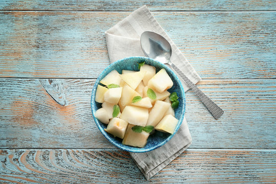 Bowl with yummy melon slices on wooden table