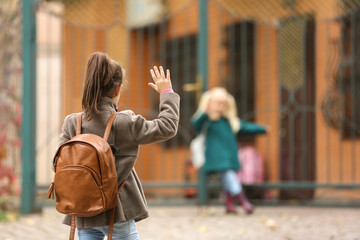 Fototapeta premium Cute little girls in outwear meeting outdoors