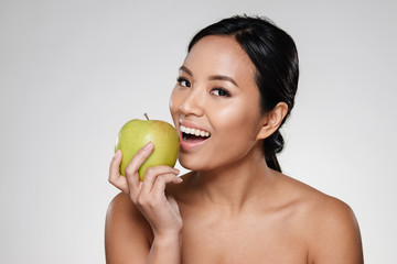 Cheerful lady smiling and eating green apple isolated