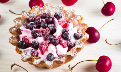 Fresh fruit and berry tart dessert with toss sugar on wooden background. Delicious sweet cake with raspberries, figs, strawberries, cherry, and cream.