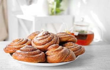 Plate with tasty cinnamon buns on table
