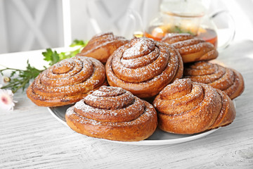 Plate with tasty cinnamon buns on table