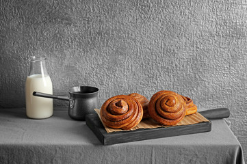 Fototapeta na wymiar Wooden board with tasty cinnamon buns on table