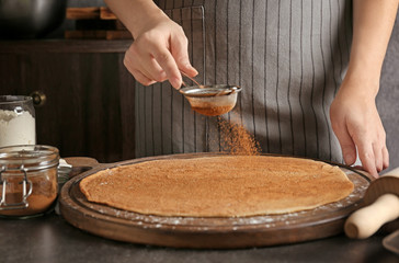 Woman preparing dough for cinnamon buns in kitchen