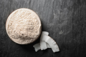 Bowl with coconut flour on textured background